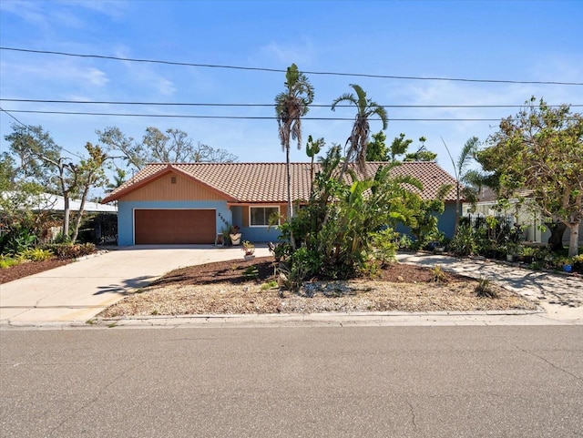 view of front of house with concrete driveway, an attached garage, and a tiled roof