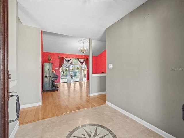 hallway with vaulted ceiling, baseboards, wood finished floors, and a notable chandelier