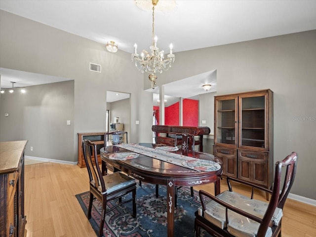 dining area with lofted ceiling, light wood-style flooring, visible vents, and baseboards