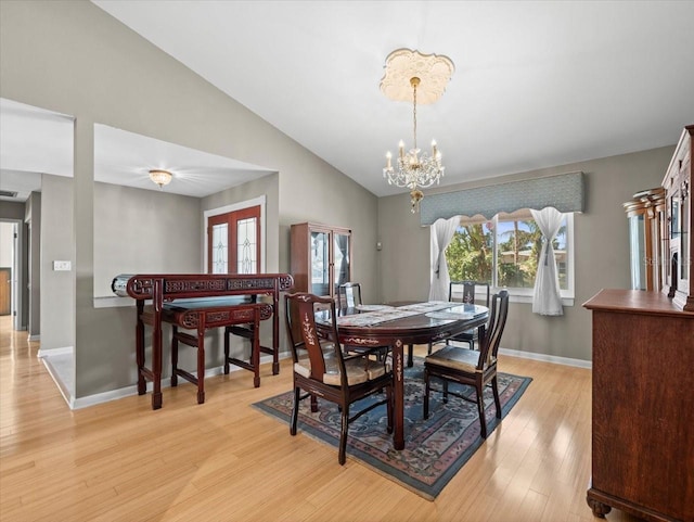 dining room with vaulted ceiling, light wood finished floors, an inviting chandelier, and baseboards