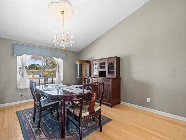 dining room with light wood-type flooring, baseboards, a chandelier, and vaulted ceiling