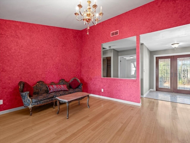 sitting room featuring french doors, a notable chandelier, visible vents, wood finished floors, and baseboards