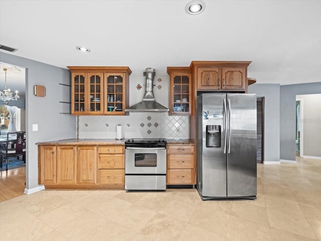 kitchen featuring visible vents, appliances with stainless steel finishes, wall chimney range hood, backsplash, and glass insert cabinets