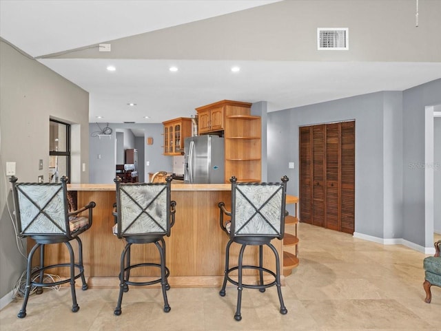 kitchen with visible vents, brown cabinets, open shelves, stainless steel fridge, and glass insert cabinets