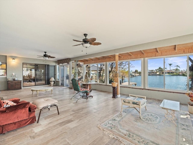 sunroom / solarium with a water view and a ceiling fan