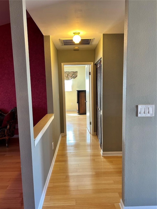 hallway featuring light wood-style flooring, visible vents, and baseboards