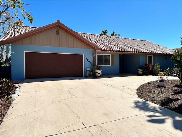 ranch-style house featuring an attached garage, concrete driveway, and a tiled roof