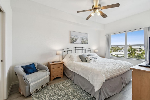 bedroom with a ceiling fan, baseboards, and wood finished floors