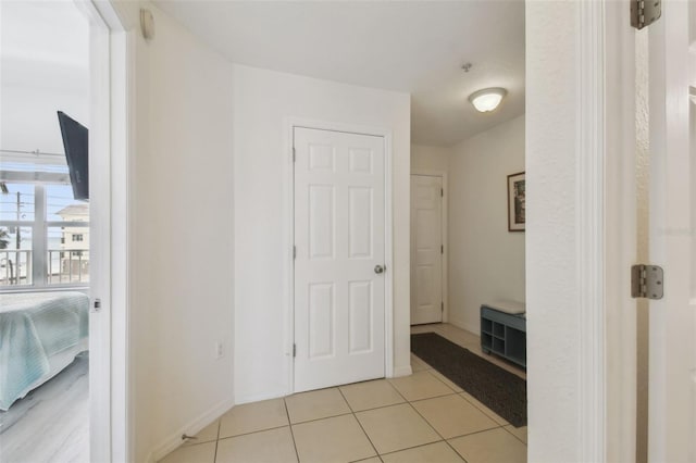 hall featuring light tile patterned floors and baseboards