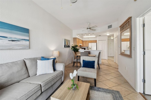 living area with light tile patterned floors, ceiling fan, visible vents, and baseboards