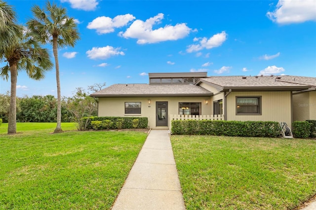 view of front of property with a shingled roof and a front lawn