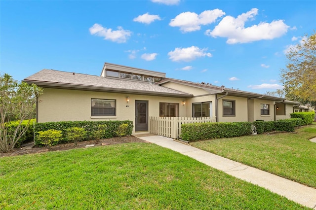 view of front of home featuring a front lawn, fence, and stucco siding