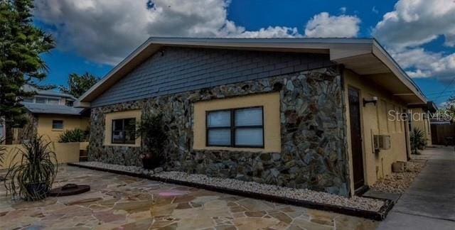 view of side of property featuring stone siding and a patio area