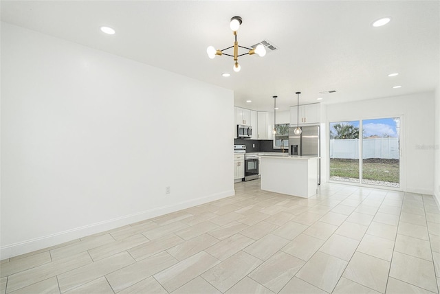 kitchen with white cabinets, a kitchen island, appliances with stainless steel finishes, light countertops, and pendant lighting