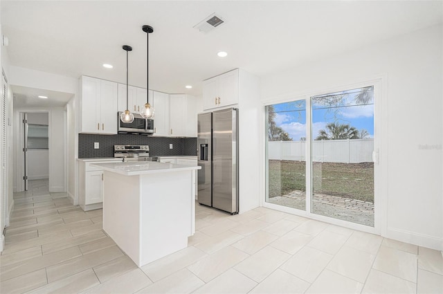 kitchen featuring stainless steel appliances, white cabinetry, hanging light fixtures, light countertops, and a center island