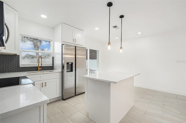 kitchen featuring appliances with stainless steel finishes, pendant lighting, light countertops, and white cabinetry