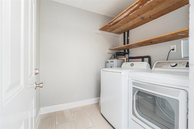 clothes washing area with laundry area, water heater, baseboards, and washing machine and clothes dryer