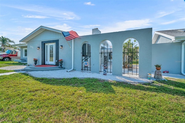 rear view of property featuring a yard, a chimney, and stucco siding