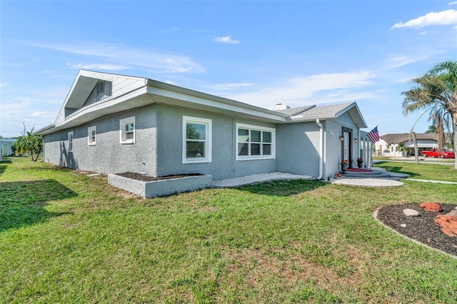 view of side of property with a lawn and stucco siding