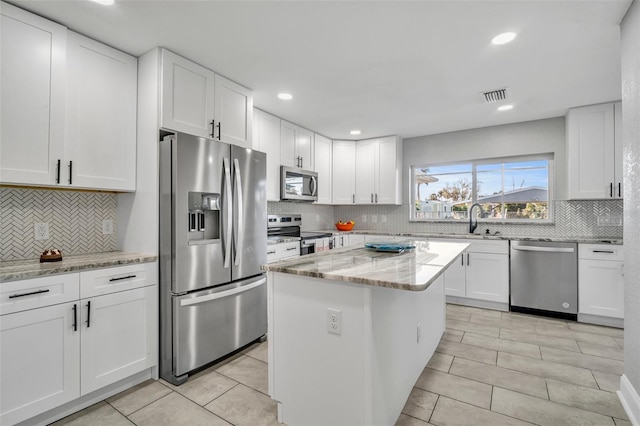 kitchen featuring stainless steel appliances, white cabinets, visible vents, and light stone counters