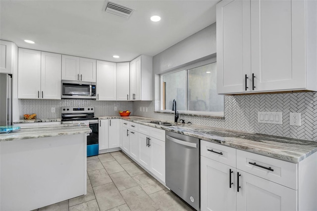 kitchen featuring visible vents, white cabinets, appliances with stainless steel finishes, light stone counters, and a sink