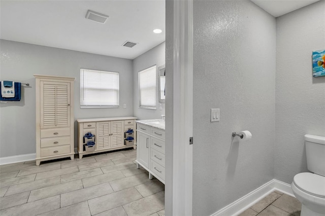 bathroom with visible vents, vanity, toilet, and baseboards