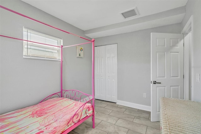 bedroom with light tile patterned floors, a closet, visible vents, and baseboards