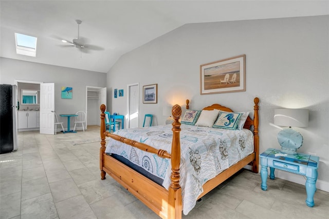 bedroom featuring a closet, freestanding refrigerator, ceiling fan, vaulted ceiling with skylight, and baseboards