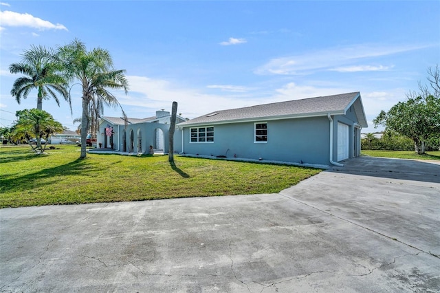 view of home's exterior with a garage, a yard, and stucco siding