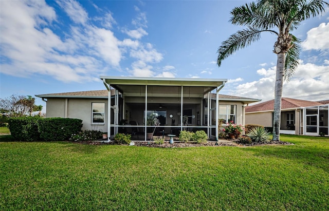 back of house with a sunroom, stucco siding, and a yard