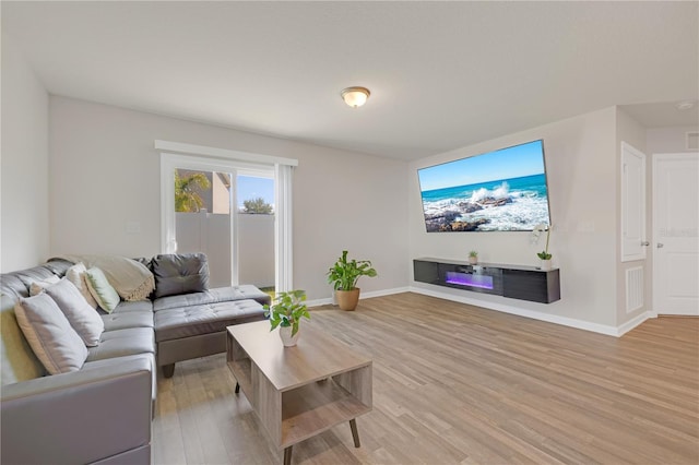 living area featuring light wood-style floors, visible vents, and baseboards