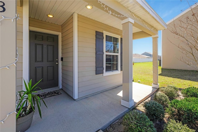 view of exterior entry featuring covered porch and a yard