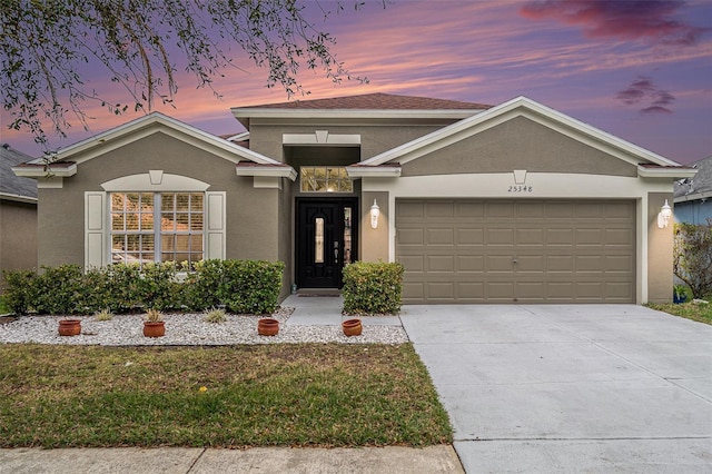 view of front facade with an attached garage, concrete driveway, and stucco siding