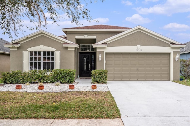 view of front of property featuring an attached garage, concrete driveway, and stucco siding