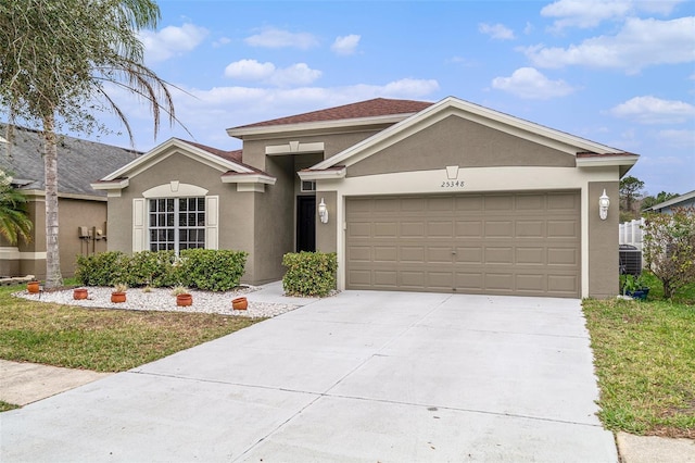 ranch-style home with a garage, cooling unit, concrete driveway, and stucco siding