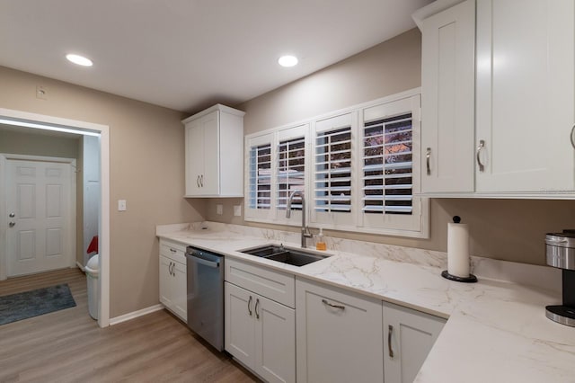 kitchen with light wood-style flooring, stainless steel dishwasher, white cabinetry, a sink, and light stone countertops