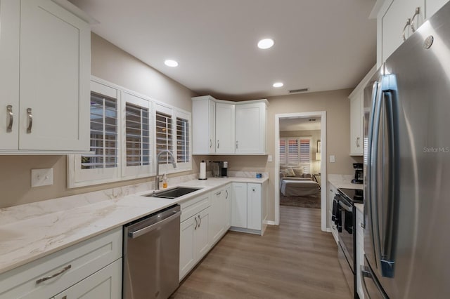 kitchen with appliances with stainless steel finishes, white cabinetry, a sink, and visible vents