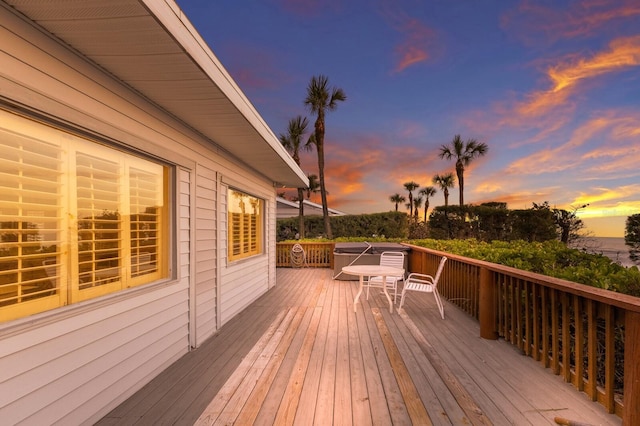 deck at dusk featuring a jacuzzi