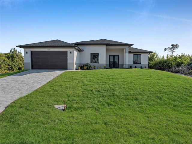 prairie-style house with an attached garage, french doors, decorative driveway, stucco siding, and a front yard