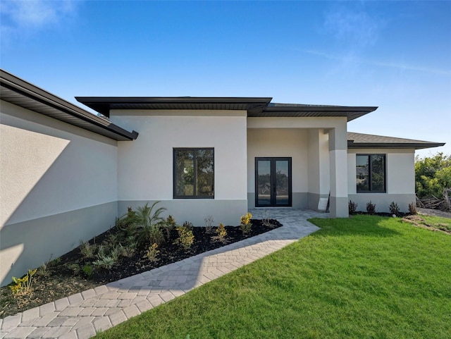 exterior space featuring a yard, stucco siding, and french doors