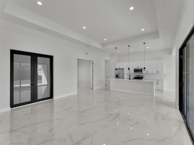 unfurnished living room featuring a raised ceiling, marble finish floor, and french doors