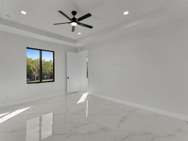 unfurnished room featuring recessed lighting, a raised ceiling, marble finish floor, and baseboards