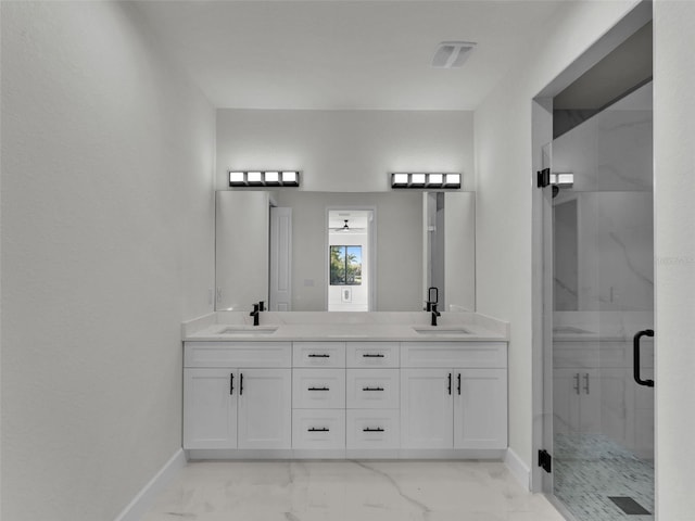 full bath featuring double vanity, marble finish floor, a shower stall, and a sink