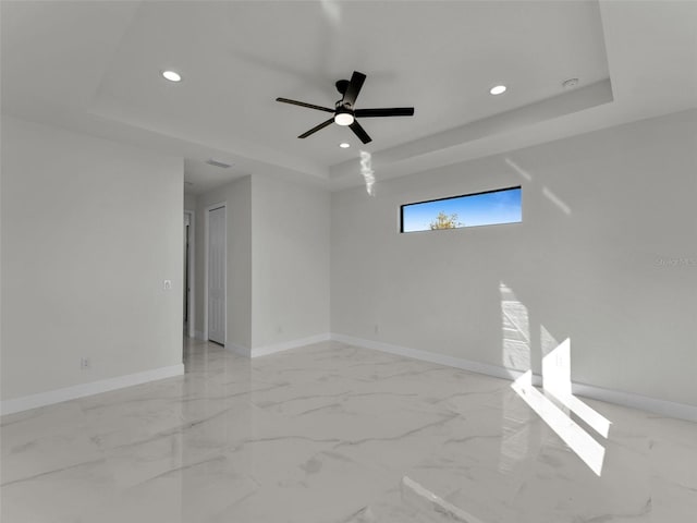 spare room featuring marble finish floor, recessed lighting, a raised ceiling, ceiling fan, and baseboards