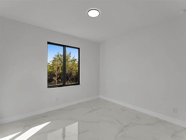 empty room featuring marble finish floor and baseboards