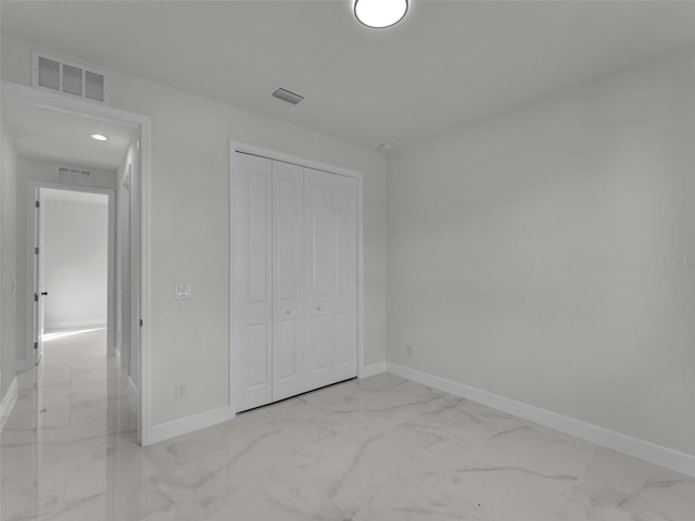 unfurnished bedroom with a closet, marble finish floor, visible vents, and baseboards