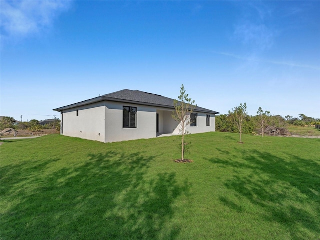 rear view of house with a lawn and stucco siding