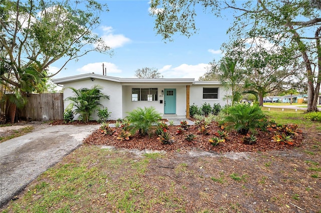 ranch-style house featuring driveway, fence, and stucco siding