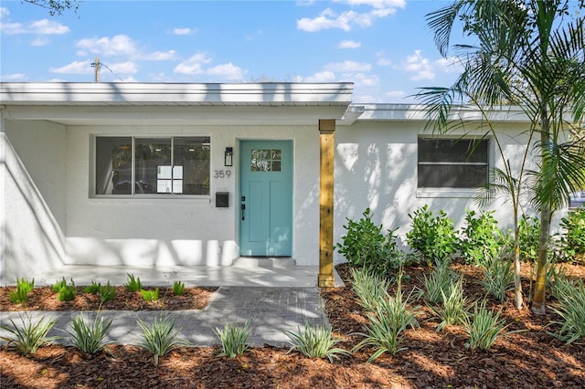 doorway to property with a porch and stucco siding