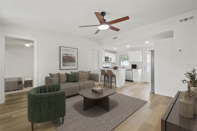 living area featuring light wood-style flooring, recessed lighting, visible vents, and a ceiling fan